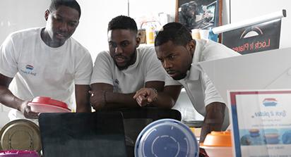 Three students looking at a laptop working.